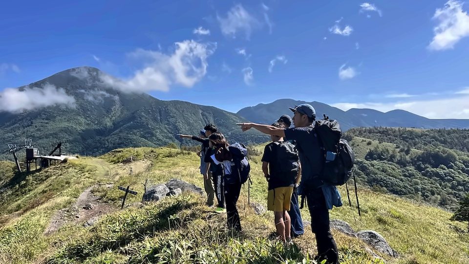 霧ヶ峰の草原で山並みを案内するガイド
