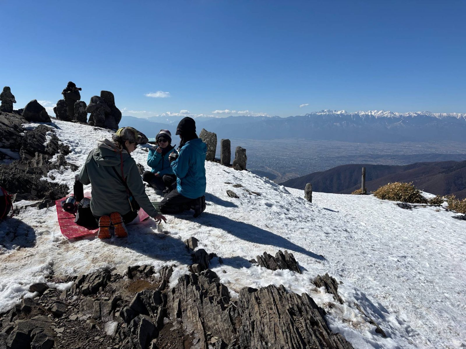 雪の美ヶ原の山頂でひと休みする参加者
