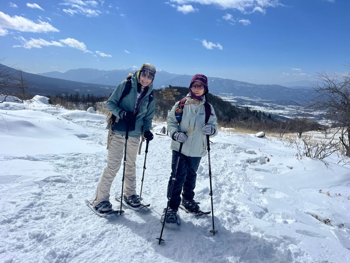雪の高原をスノーシューで歩く2人と山並み